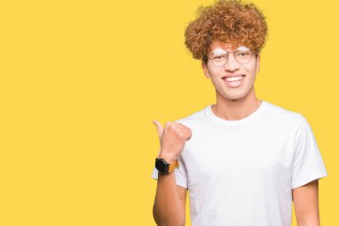 Afro saçlı gözlüklü seyir ve başparmak yanında yukarıyı mutlu yüz ile gülümseyen yakışıklı delikanlı.