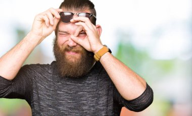 Genç hipster adam giyen güneş gözlüğü el gülümseyen, ok jest yapıyor göz parmakları ile mutlu yüz üzerinden seyir.