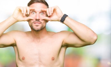 Gömleksiz yakışıklı gösteren çıplak göğüs parmaklarıyla, uykulu ve sabah yorgunluk için yorgun gözlerini açmaya çalışıyor