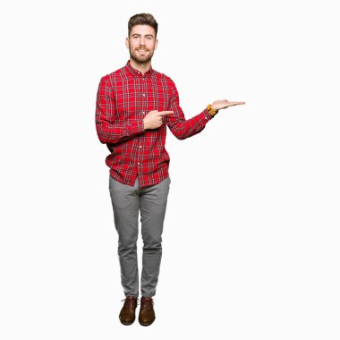 Hayret ve el ile sunulması ve parmak ile işaret ederken kameraya gülümseyen yakışıklı delikanlı.