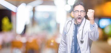 Yakışıklı genç doktor adam izole arka plan öfkeli ve sinirli sinirli ve öfke ile bağırarak süre öfkeli yumruk yükselterek. Öfke ve agresif kavramı.