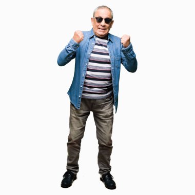 Denim ceket ve kutlama güneş gözlüğü takan yakışıklı komuta sizde şaşırttı ve başarı için kaldırdı kollarını açarak hayret ve gözleri açık. Kazanan kavramı.