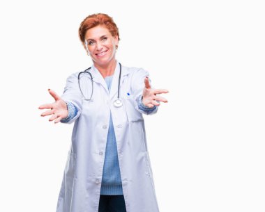 Sarılmak için kollarını açarak gülümseyerek kameraya bakarak izole arka plan üzerinde tıbbi üniforma giyen üst düzey beyaz doktor kadın. Neşeli ifade kucaklayan mutluluk.