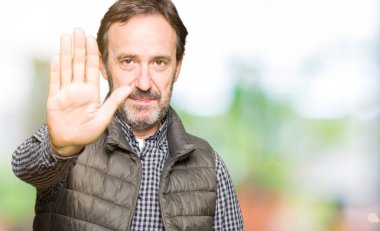 Orta yaş yakışıklı adam kış yeleği elin avuç durağı şarkı yapıyor. Negatif ve ciddi bir jest yüz ifadesiyle uyarı.