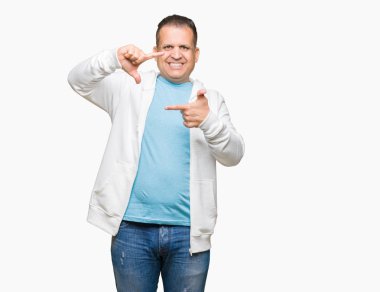 Orta yaş Arap adam elleriyle yapım çerçeve ve parmakları ile mutlu yüz gülümseyen izole arka plan üzerinde kazak giyiyor. Yaratıcılık ve Fotoğrafçılık kavramı.