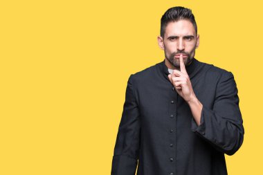İzole arka plan üzerinde genç Hıristiyan rahip dudaklarında parmak ile sessiz olmak istiyor. Sessizlik ve gizli konsept.