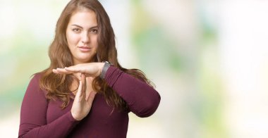 Güzel ve çekici artı boyutu genç kadın bir elbiseyle izole arka plan yapıyor zaman aşımı jest elle, sinirli ve ciddi bir yüz üzerinden