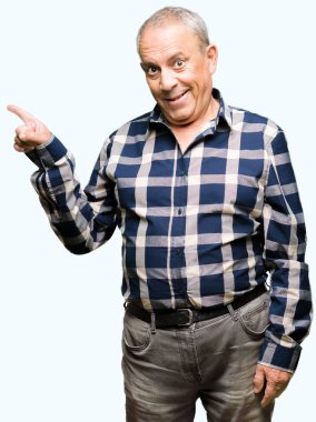 Yüzünde büyük bir gülümseme ile rahat gömlek giyen yakışıklı kıdemli adam, kamera bakarak yan el ve parmak ile işaret.