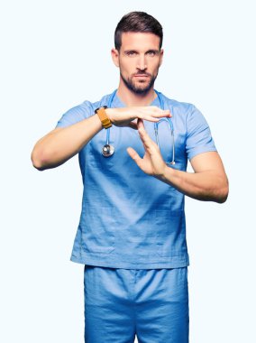 Yakışıklı Doktor adam izole arka plan yapıyor zaman aşımı jest elle, sinirli ve ciddi bir yüz üzerinde tıbbi üniforma