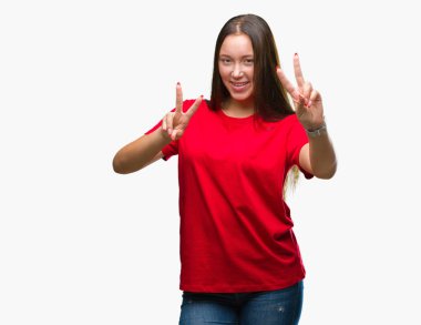 Genç güzel beyaz kadın parmaklarını zafer işareti yaparken gösterilen kamera seyir gülümseyen izole arka plan yüzünden. İki numaralı.