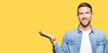 Yakışıklı adam mavi gözleri ve neşeli sunulması ve kameraya bakarak avucunun ile işaret gülümseyen denim ceket giyen sakal.