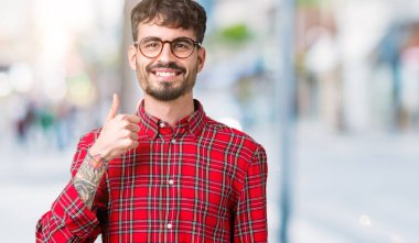 Hareketi el ile mutlu yaşasın yapıyor izole arka plan üzerinde gözlük takan yakışıklı delikanlı. Başarı gösteren kameraya bakarak ifade onaylama.