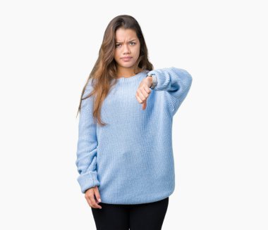 Genç güzel esmer kadın izole arka plan üzerinde mavi kış kazak giyiyor mutsuz ve öfkeli gösteren reddetme ve başparmak aşağı jest ile negatif bakıyor. Kötü ifade.