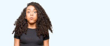 Komik surat ile yanakları şişirme kıvırcık saçlı Genç güzel kadın. Ağız ile hava, deli ifade şişirilmiş.