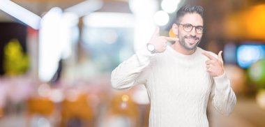 Kendinden emin gösterilen ve işaret parmakları diş ve ağız ile gülümseyen izole arka plan üzerinde gözlük takan yakışıklı delikanlı. Sağlık kavramı.