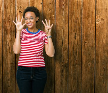 Güzel genç Afro-Amerikan kadın gözlük gösterilen ve parmakları ile işaret izole arka plan üzerinde dokuz kendinden emin ve mutlu gülümseyerek iken numara.