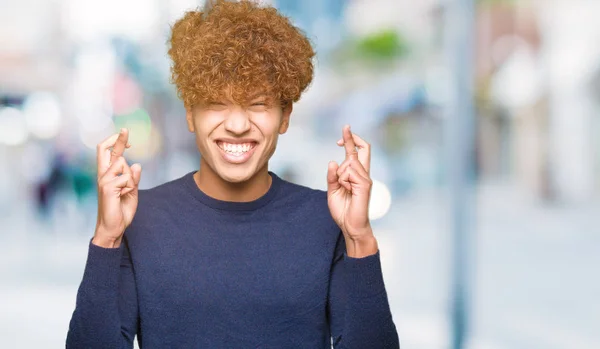 Joven Hombre Guapo Con Pelo Afro Sonriendo Cruzando Los Dedos — Foto de Stock