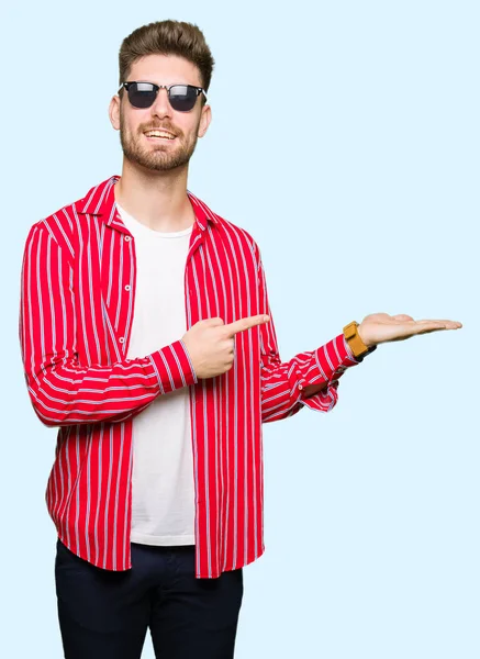 Young Handsome Man Wearing Sunglasses Amazed Smiling Camera While Presenting — Stock Photo, Image