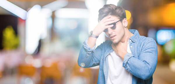 Young handsome man wearing sunglasses over isolated background Touching forehead for illness and fever, flu and cold, virus sick