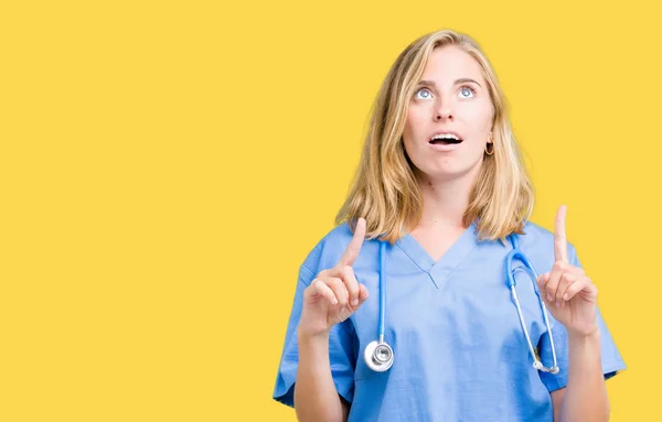 Hermosa Joven Doctora Vistiendo Uniforme Médico Sobre Fondo Aislado Asombrada —  Fotos de Stock