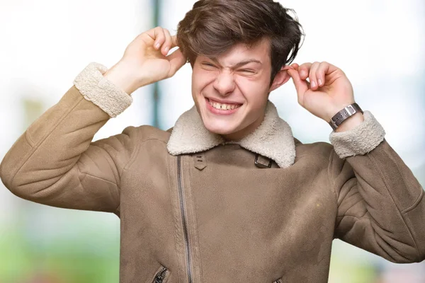 Üzerinde kış ceket giyen genç yakışıklı adam arka plan gülen çekerek kulakları parmaklar, komik jest ile izole. Seçmelere sorun