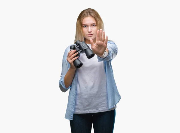 年轻的高加索妇女拿着双筒望远镜在孤立的背景与开放的手做停止标志与严肃和自信的表示 防御姿态 — 图库照片