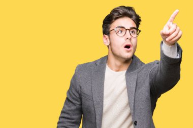 Üzerinde gözlük takan genç iş adamı izole arka plan ile sürpriz devam parmakla, açık ağız hayret ifadesi, önünde bir şey