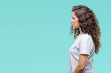 Güzel esmer kıvırcık saçlı Genç kız üzerinde rahat t-shirt giyen arka tarafına, seyir izole dinlenmek doğal yüz emin gülümseme ile pozuyla profili.