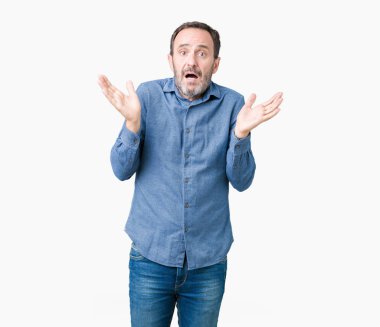 Yakışıklı orta yaş izole arka plan clueless ve şaşkın bir ifadeyle kollar ve eller kaldırdı üzerinde zarif komuta sizde. Şüphe kavramı.