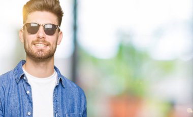 Hayret ve el ile sunulması ve parmak ile işaret ederken kameraya gülümseyen denim ceket giyen genç yakışıklı zarif adam.