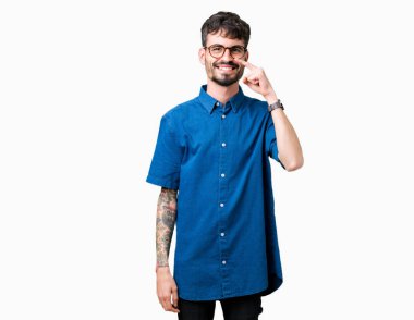 Genç yakışıklı adam gözlük izole üzerinde işaretleme için yüz ve burun, neşeli gülümseyerek el parmak ile arka plan