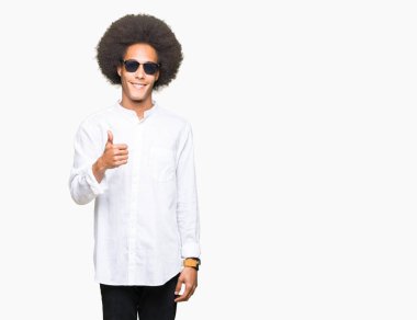 Afrikalı-Amerikalı genç afro saçlı hareketi el ile mutlu yaşasın yaparken güneş gözlüğü takıyor. Kameraya bakarak başarı gösteren ile ifade onaylama.