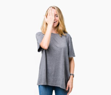 Güzel genç kadın üzerinde büyük boy rahat t-shirt giyen arka plan kapsayan bir göz yüz ve sürpriz duygu kendinden emin gülümseme ile el ile izole.