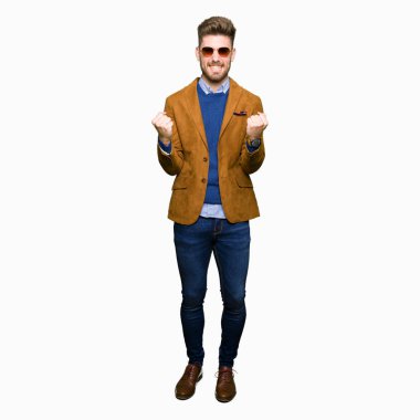 Genç yakışıklı zarif adam kutluyor güneş gözlüğü takıyor şaşırttı ve silah ile başarı için yükseltilmiş ve açık gözler hayrete düşürdü. Kazanan kavramı.