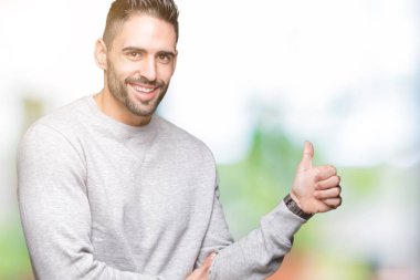 Tarafa jest yapıyor gülümseyen genç yakışıklı adam kazak giyiyor gurur, seyir izole arka plan üzerinde yaşasın