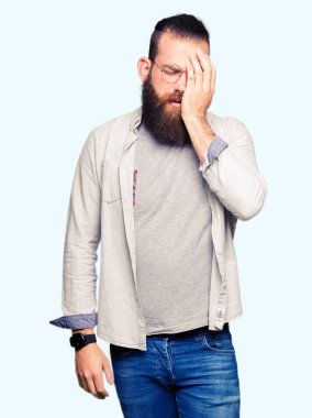 Yarım yüz, göz ve ağız el ile kapsayan yorgun esneme gözlüklü genç sarışın adam. Acı yüzü acıyor.