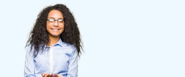 Kıvırcık saçlı giyen ile genç güzel iş kız alma veya jest vererek birlikte el avuç içi ile gülen gözlük. Ayrı tutma ve koruma