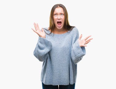 Üzerinde kış kazak giyen genç güzel beyaz kadın arka plan deli izole ve deli bağırarak ve agresif ifade ve silah kaldırdı bağırıyor. Hayal kırıklığı kavramı.