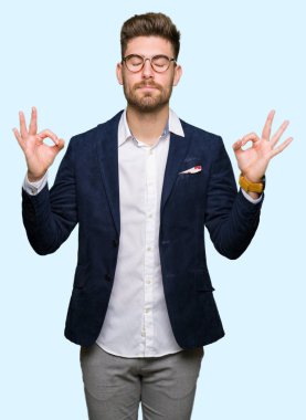 Genç yakışıklı iş adam gözlük rahatla ve gülümseyen gözlerle kapalı parmak jestle meditasyon yapıyor. Yoga kavramı.