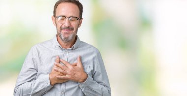 Göğüs kapalı gözler ve yüzünde minnettar jest ile gülümseyen izole arka plan üzerinde gözlük takan yakışıklı orta yaş zarif komuta sizde eller. Sağlık kavramı.