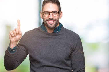 Ve kendinden emin ve mutlu gülümseyerek süre parmak numaralı yukarıyı gösteren izole arka plan üzerinde gözlük takan genç yakışıklı adam.