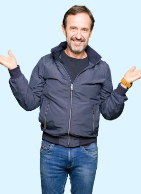 Gülen iki elle gösterilen avuç içi, sunma ve karşılaştırma ve denge reklam açık bir ceket giyen orta yaş yakışıklı adam