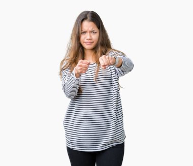 İzole arka planda çizgili kazak giyen genç güzel esmer kadın mücadele, agresif ve öfkeli saldırı, tehdit ve şiddet yumruk Punch