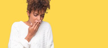 İzole arka plan üzerinde kış kazak giyen güzel genç Afro-Amerikan kadın el ağzıyla kapsayan yorgun esneme sıkılmış. Restless ve uyku hali.