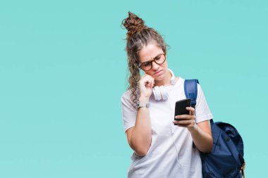Sırt çantası, kulaklık ve smartphone izole arka plan ciddi bir yüz düşünme hakkında soru, çok karışık bir fikir üzerinde giyen genç esmer öğrenci kız