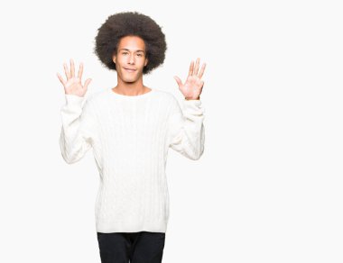 Gösterilen ve parmakları ile işaret afro saç giyen kış kazaklı genç Afro-Amerikan adam numara 9 kendinden emin ve mutlu gülümseyerek süre.