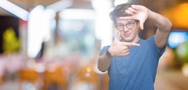 Elle yapma çerçeve ve parmakları ile mutlu yüz gülümseyen izole arka plan üzerinde gözlük takan yakışıklı delikanlı. Yaratıcılık ve Fotoğrafçılık kavramı.