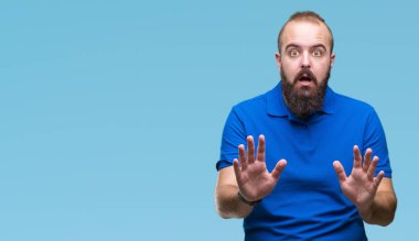 Üzerinde mavi gömlek giymiş genç beyaz hipster adam arka plan korkuyor ve korku ifade dur hareketi el ile ile dehşete şokta bağırarak izole. Panik kavramı.