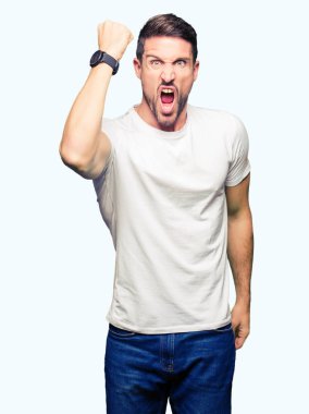 Yakışıklı adam kızgın ve deli yumruk hayal kırıklığı ve öfke ile bağırarak süre öfkeli yükselterek Casual beyaz t-shirt giyiyor. Öfke ve agresif kavramı.