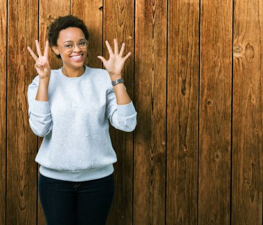 Genç güzel Afrikalı-Amerikalı kadın gözlük gösterilen ve parmakları ile işaret izole arka plan üzerinde kendinden emin ve mutlu gülümseyerek süre sekiz numara.